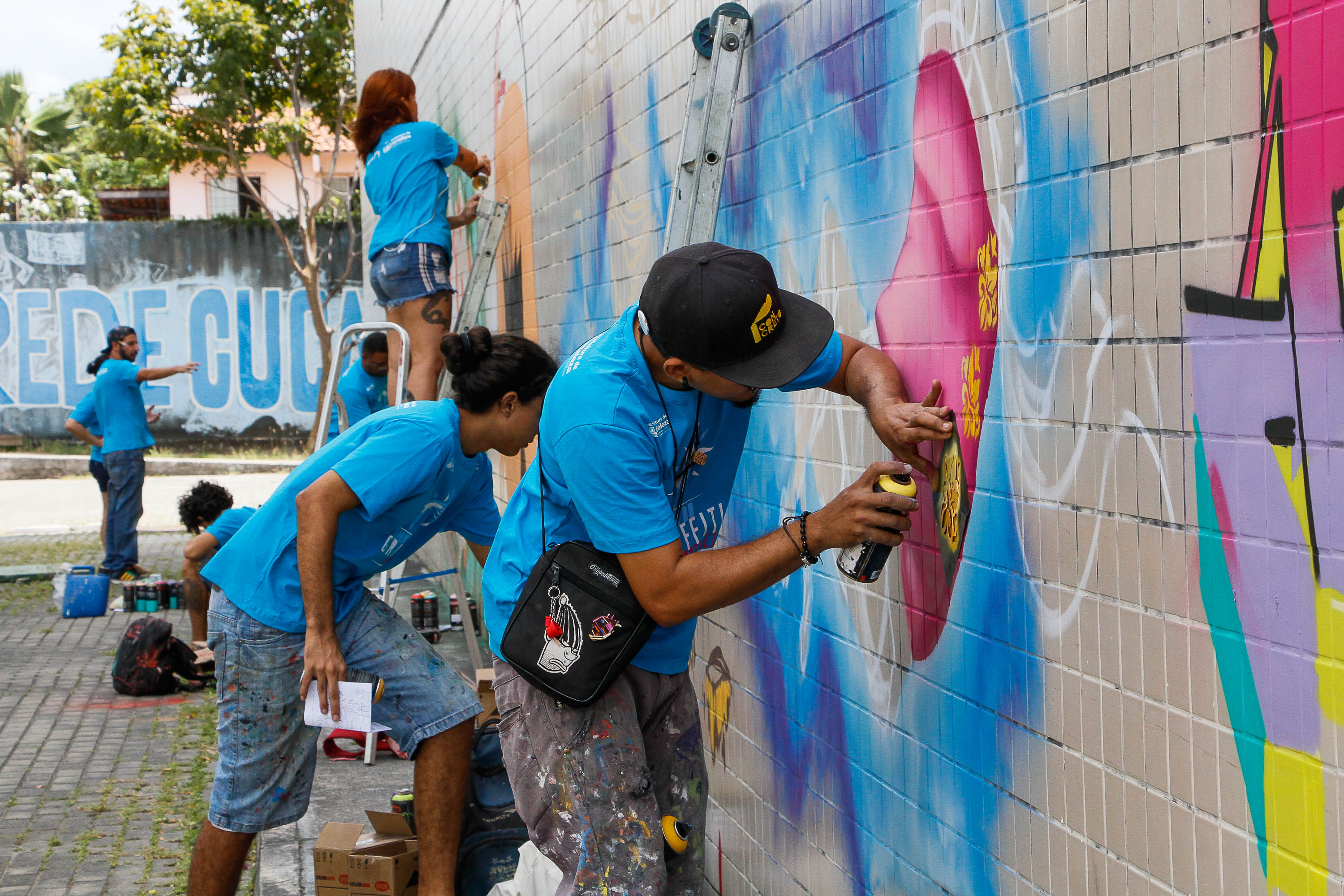 um grupo de pessoas faz grafites num muro